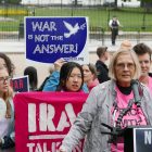 Image of a protest against war with Iran. Woman speaking at podium