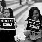 Two black girls holding signs that say "Black Lives Matter"