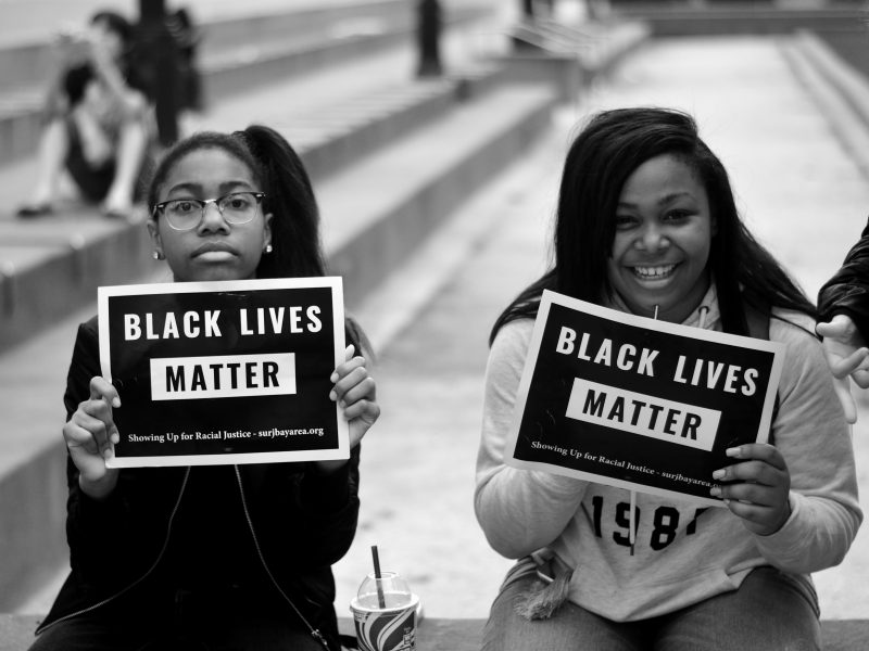 Two black girls holding signs that say "Black Lives Matter"