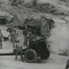 grayscale photo of men standing near cannon