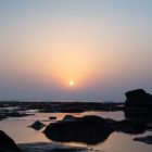 silhouette of rocks on sea shore during sunset