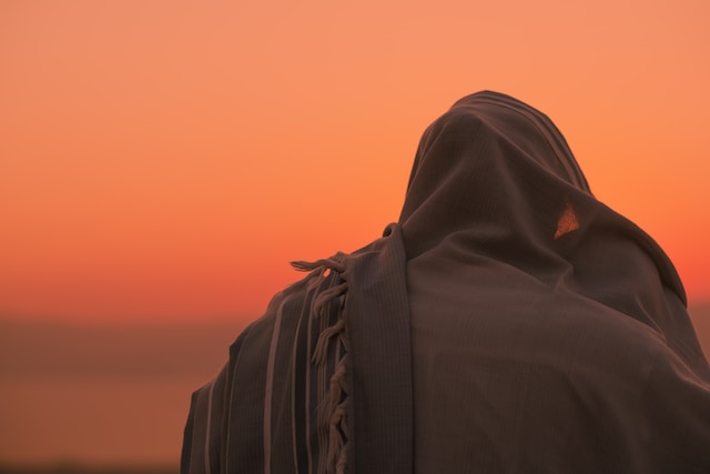 A husband and wife huddle together under the husband's prayer shawl after his sunrise prayer at Masada, Israel.